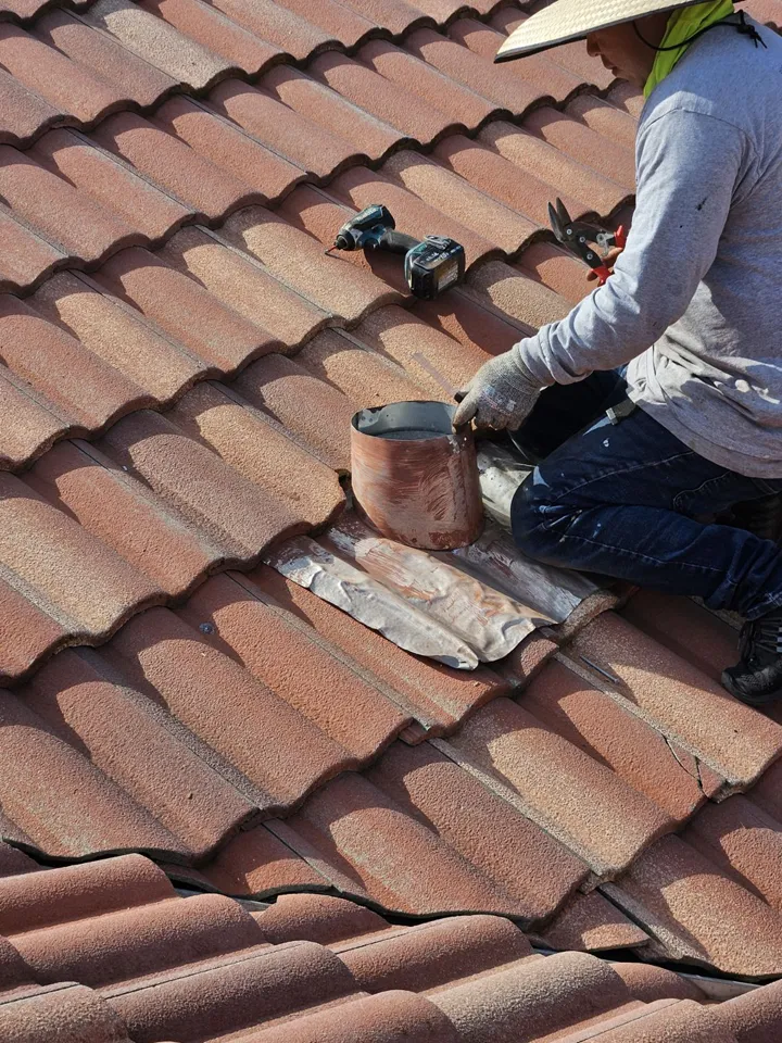 A skilled construction worker repairing roof tiles to fix leaking roof