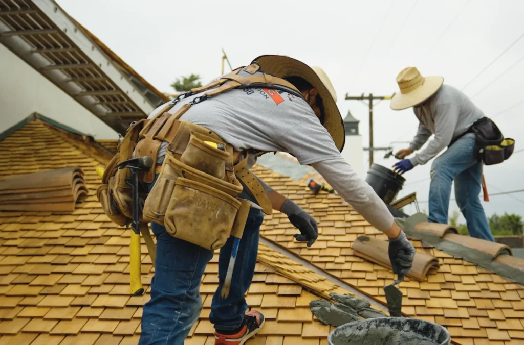 Worker replacing wood shingle roof with tile ridges